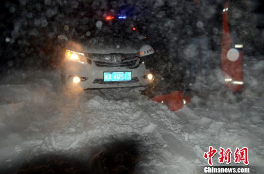圖為消防人員跪在雪地里用鐵鍬鏟雪救援被困車(chē)輛?！±罱z